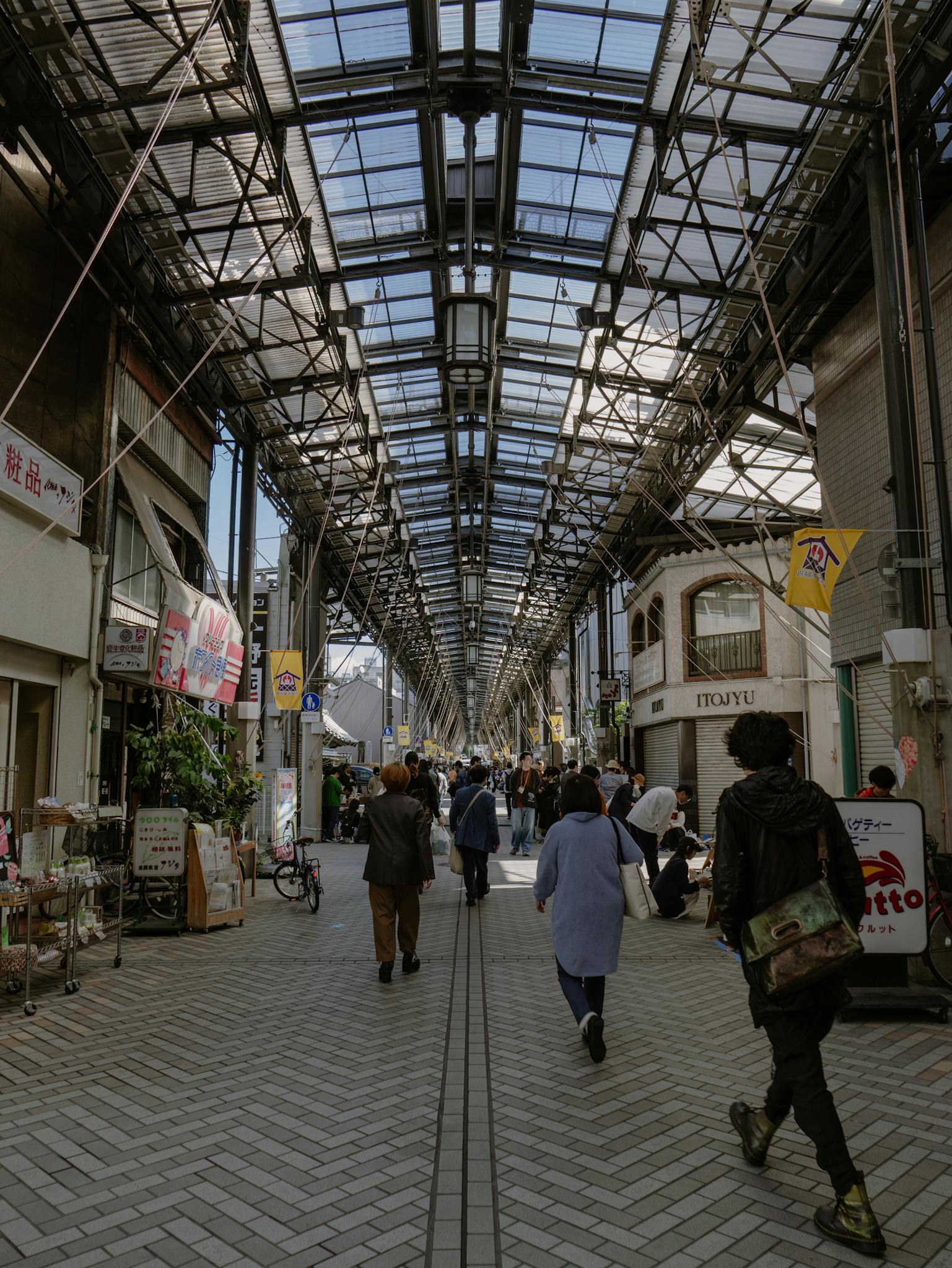 Pedestrians stroll through a vibrant shopping street in Nagoya, Japan, under a glass ceiling.